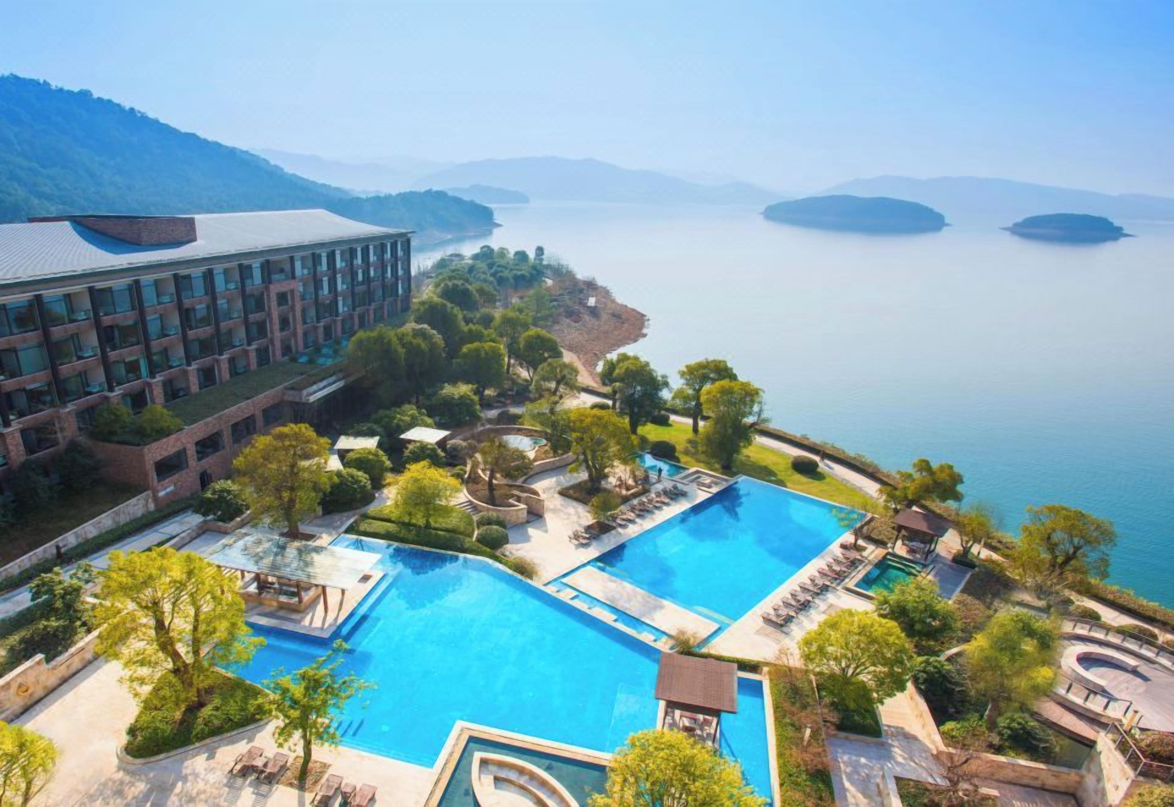 Un hotel con varias piscinas, un edificio grande y vista al mar.