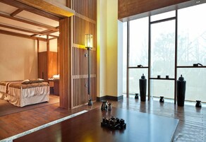 A room with a bed, a wooden partition, and a large window.