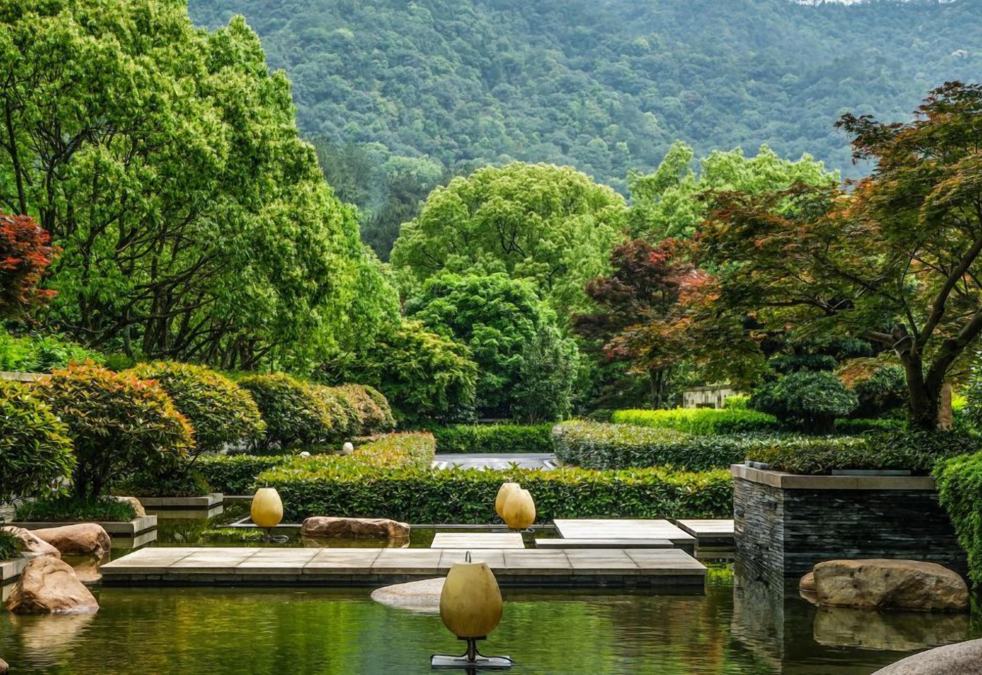 Un jardin paisible avec un étang, des allées pavées et une végétation luxuriante.