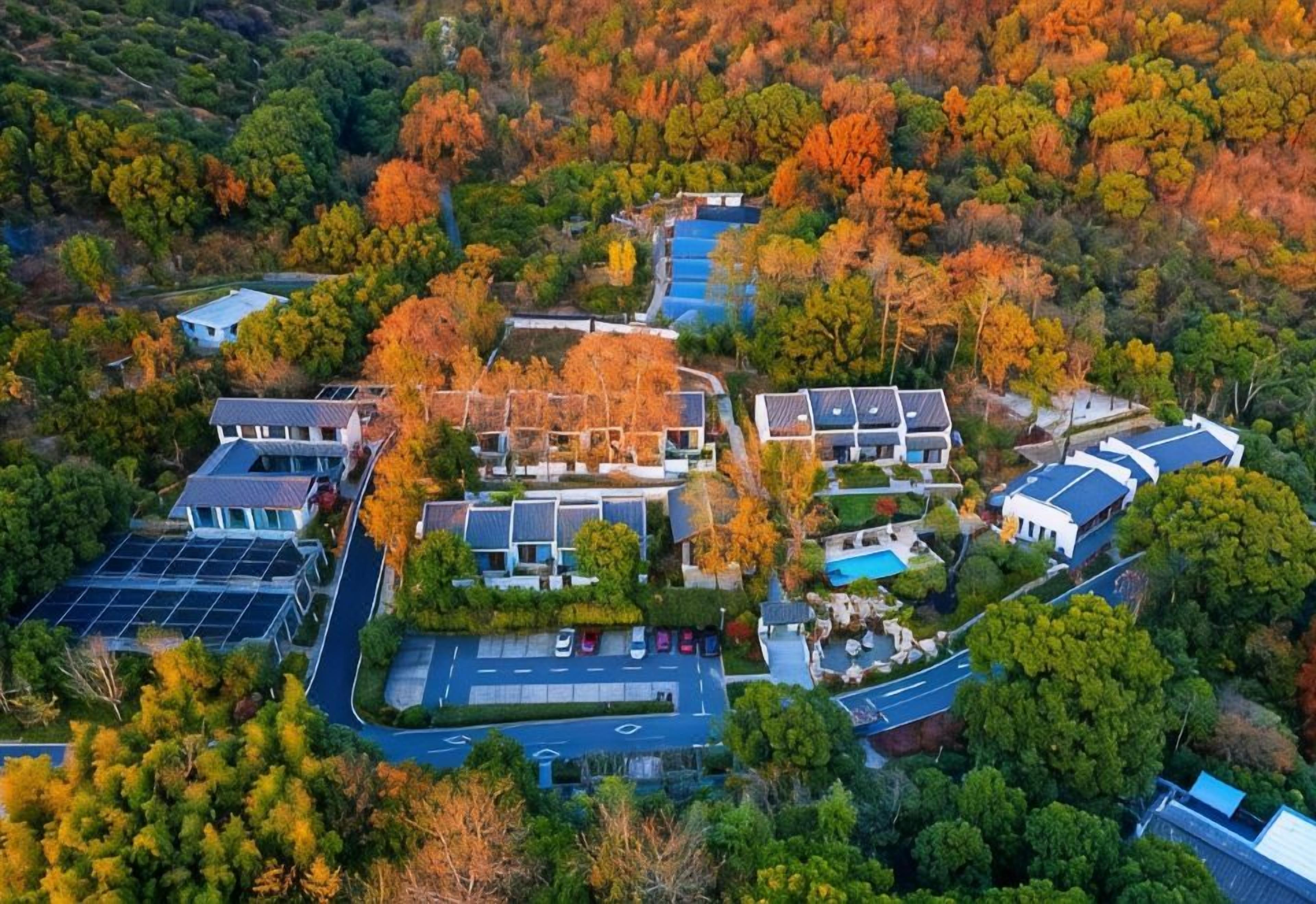 Vista aérea de una zona residencial con casas modernas, un estacionamiento y una piscina.