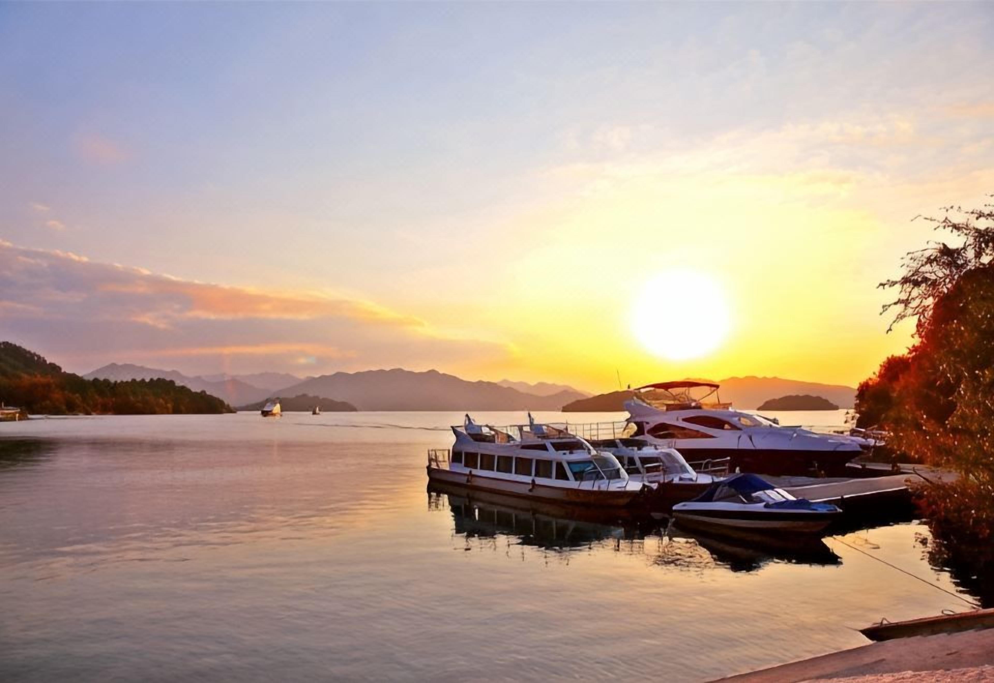 Un lago tranquilo con barcos amarrados en un muelle durante el atardecer.