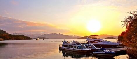 Un lago tranquilo con barcos amarrados en un muelle durante el atardecer.