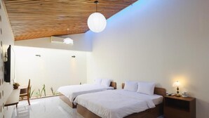 A modern hotel room with two beds, a wooden ceiling, a small table, and a nightstand with a lamp. - SON HAI HOMESTAY (Hue)