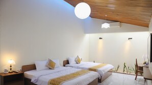 A hotel room with two beds, a desk, a chair, a lamp, and a ceiling light. - SON HAI HOMESTAY (Hue)