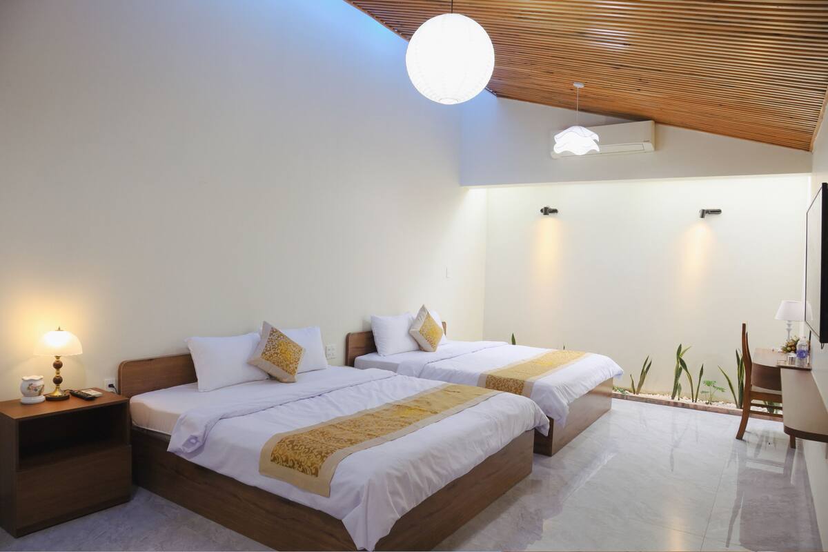 Habitación de hotel con dos camas, un escritorio, una silla, una lámpara y una luz en el techo.