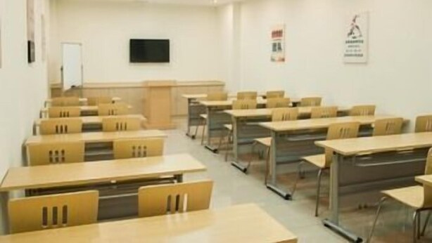A classroom with rows of desks and chairs, a whiteboard, and a television on the wall. - Greentree Inn (Suzhou)