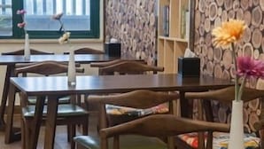 A restaurant interior with wooden tables and chairs, a patterned wall, and a window with a view. - Greentree Inn (Suzhou)