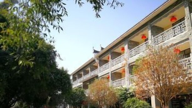 Un immeuble à plusieurs étages doté de balcons, une rue devant et des arbres.