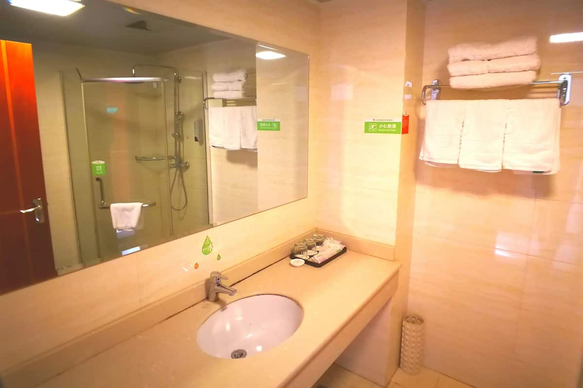 A bathroom with a sink, mirror, and glass shower enclosure.