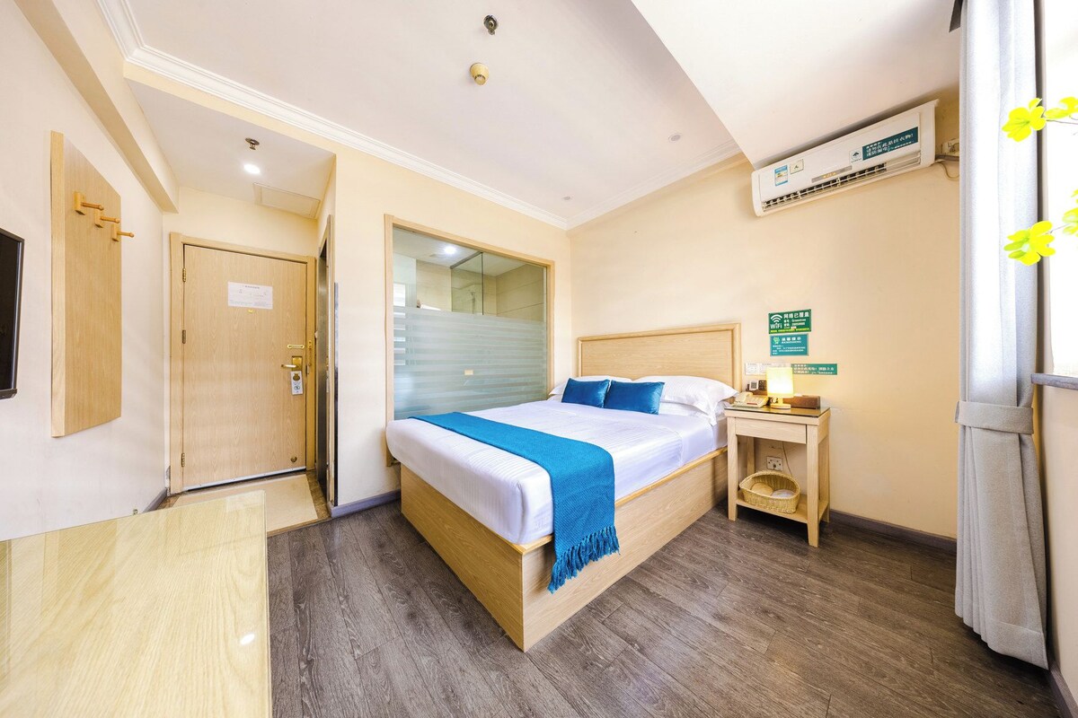 A hotel room with a bed, bedside table, and a window with curtains.