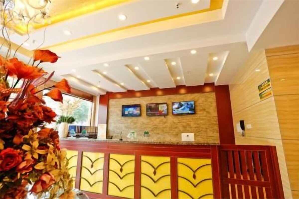 A reception desk with a modern design, a mounted television, and a decorative plant arrangement.