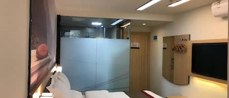 A hotel room with a bed, bedside table, wall-mounted TV, and a mirror.