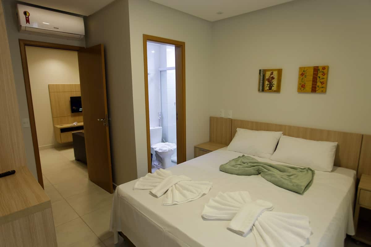 Habitación de hotel con cama, escritorio, silla, inodoro y ducha.
