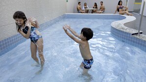 A swimming pool with tiled walls and a curved edge. - Everest Flat Service (Caldas Novas)