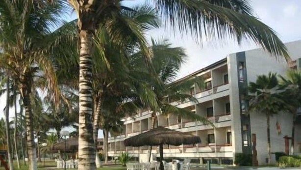 Resort com piscina, palmeiras e um edifício com varandas.