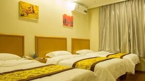 A hotel room with three beds, a headboard, a wall-mounted air conditioner, and a window with curtains. - Greentree Inn (Tangshan)