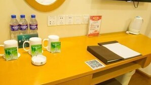 A reception desk with a yellow counter, a television mounted on the wall, a coffee machine, and a few water bottles. - Greentree Inn (Tangshan)