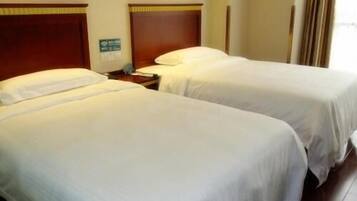 A hotel room with two beds, wooden headboards, a nightstand, and a green sign on the wall.