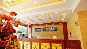 A reception desk with a modern design, a mounted television, and a decorative plant arrangement. - Greentree Inn (Tangshan)