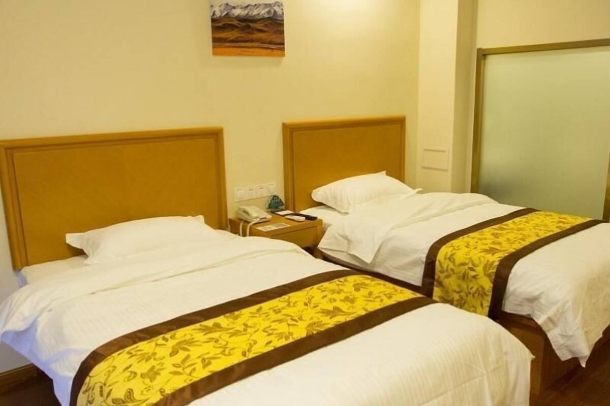 A hotel room with two beds, a nightstand, a phone, and a painting on the wall.