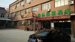 Hotel con letrero, unidades de aire acondicionado y un coche estacionado adelante.