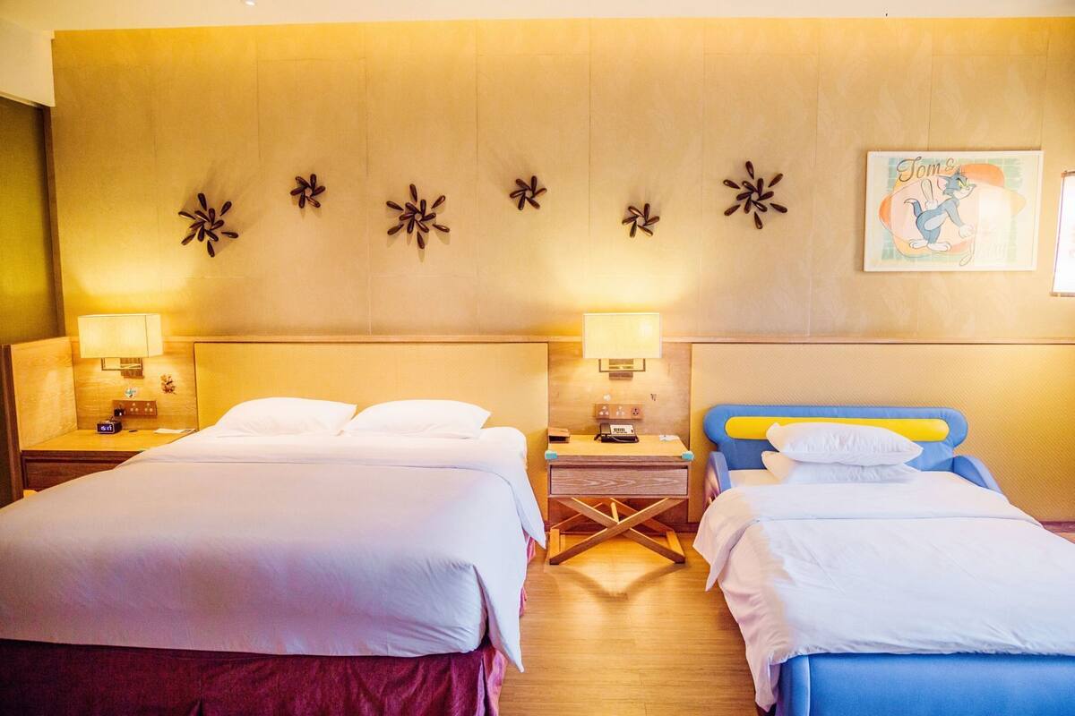 Habitación de hotel con dos camas, mesitas de noche, lámparas y un adorno en la pared.