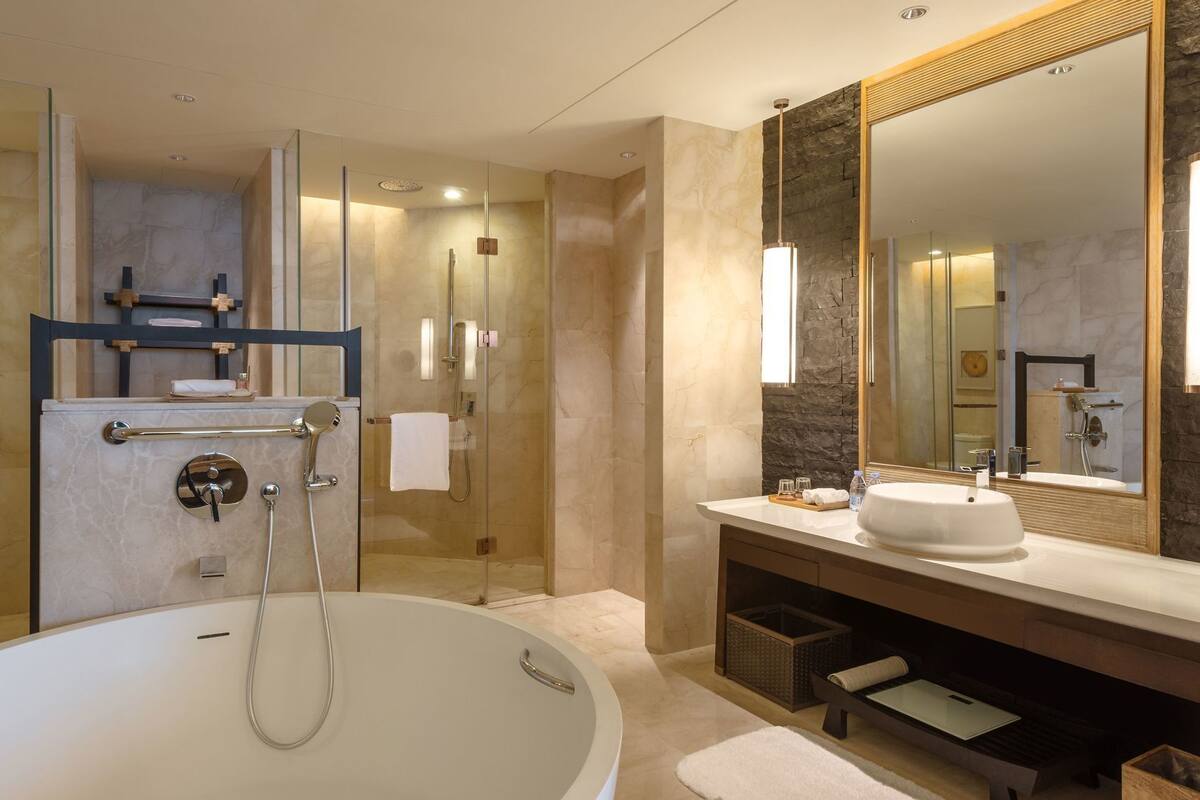 Un baño moderno con una bañera independiente, un espejo grande y una zona de ducha con mampara de vidrio.