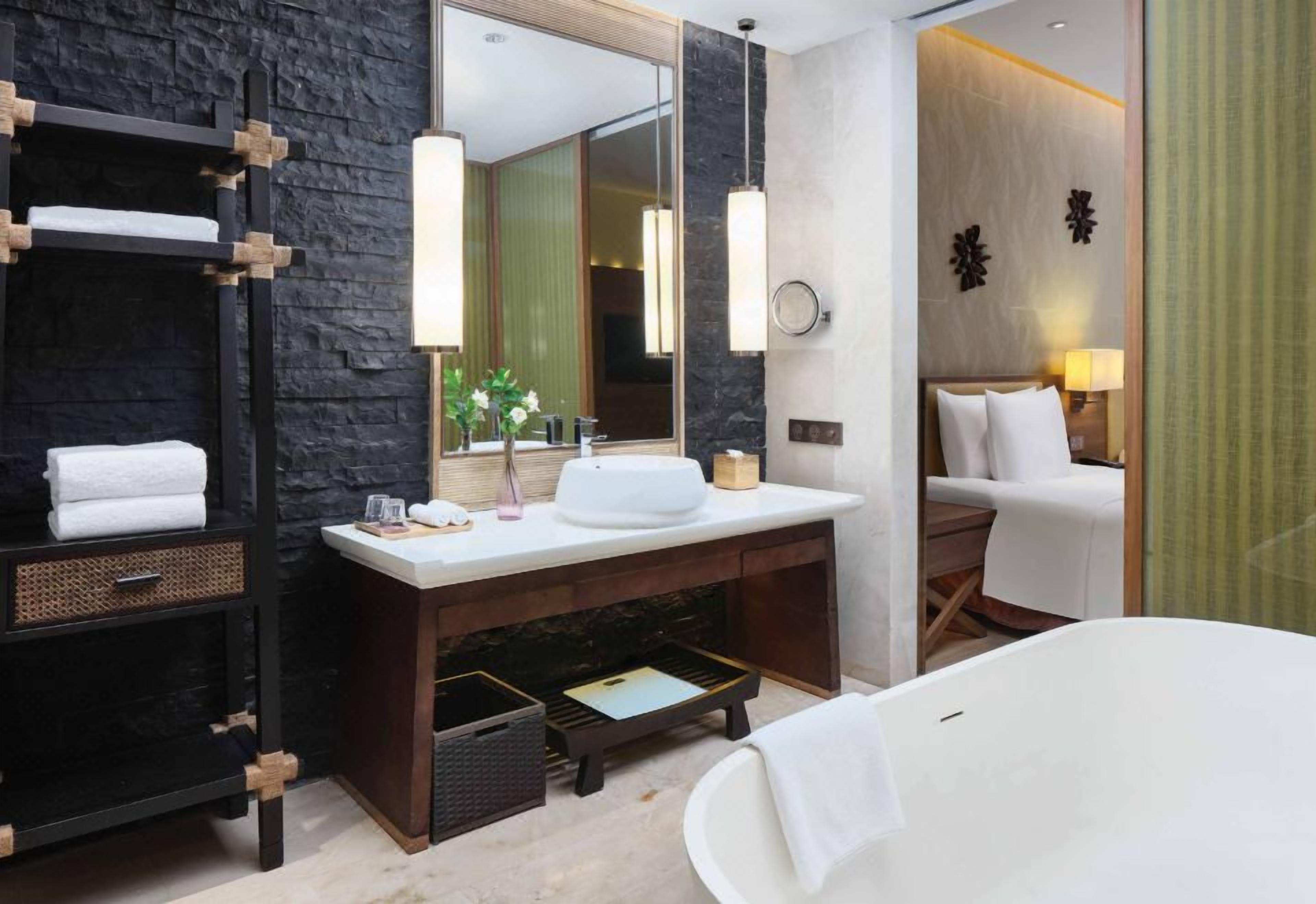 A modern bathroom with a large mirror, a white bathtub, and a wooden vanity.