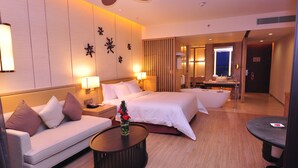 Habitación de hotel con cama, sofá, mesa de centro, baño con bañera y escritorio.