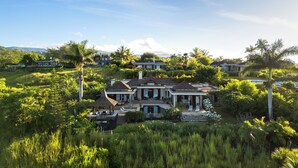 A large, multi-story house with a pool, surrounded by lush greenery and palm trees. - Spacious 4-Bedroom Ocean View Villa / Infinity Pool & Outdoor Living (Bel Ombre)