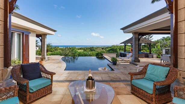A covered outdoor area with wicker furniture, a glass table, and a view of a pool and ocean. - Spacious 4-Bedroom Ocean View Villa / Infinity Pool & Outdoor Living (Bel Ombre)