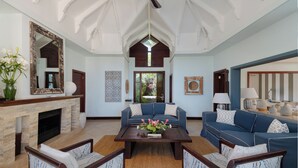 A spacious living room with a fireplace, blue sofas, and a large mirror. - Spacious 4-Bedroom Ocean View Villa / Infinity Pool & Outdoor Living (Bel Ombre)