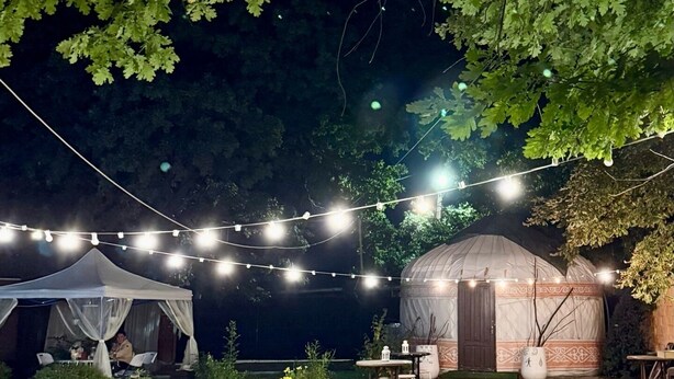 A tented outdoor area with string lights, tables, and benches. - Ethno Adventure Camp (Almaty)