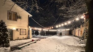 A snow-covered pathway leading to a building with string lights overhead. - Ethno Adventure Camp (Almaty)
