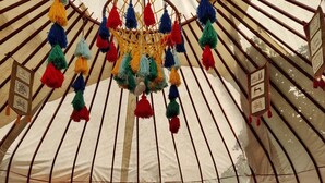 A yurt interior with a central hanging decoration, two sofas, and patterned cushions. - Ethno Adventure Camp (Almaty)