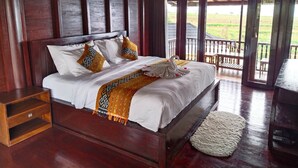 A wooden-framed bedroom with a bed, pillows, and a decorative swan pillow. - Merlyn Meadows Retreat (Munduk)
