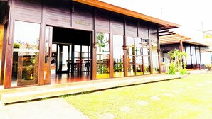 A building with a covered outdoor seating area, a name sign, and a visible entrance. - Merlyn Meadows Retreat (Munduk)