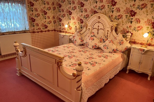 Kingsize-Bett mit Nachtschränkchen, Kleiderschrank und Schminktisch.