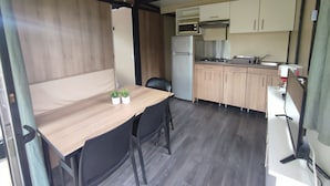 Une cuisine compacte équipée d’un réfrigérateur, d’une cuisinière, d’un four à micro-ondes et de meubles de rangement en bois.