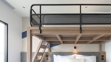 Una cama litera con escalera, una mesita de noche y una lámpara de pared.