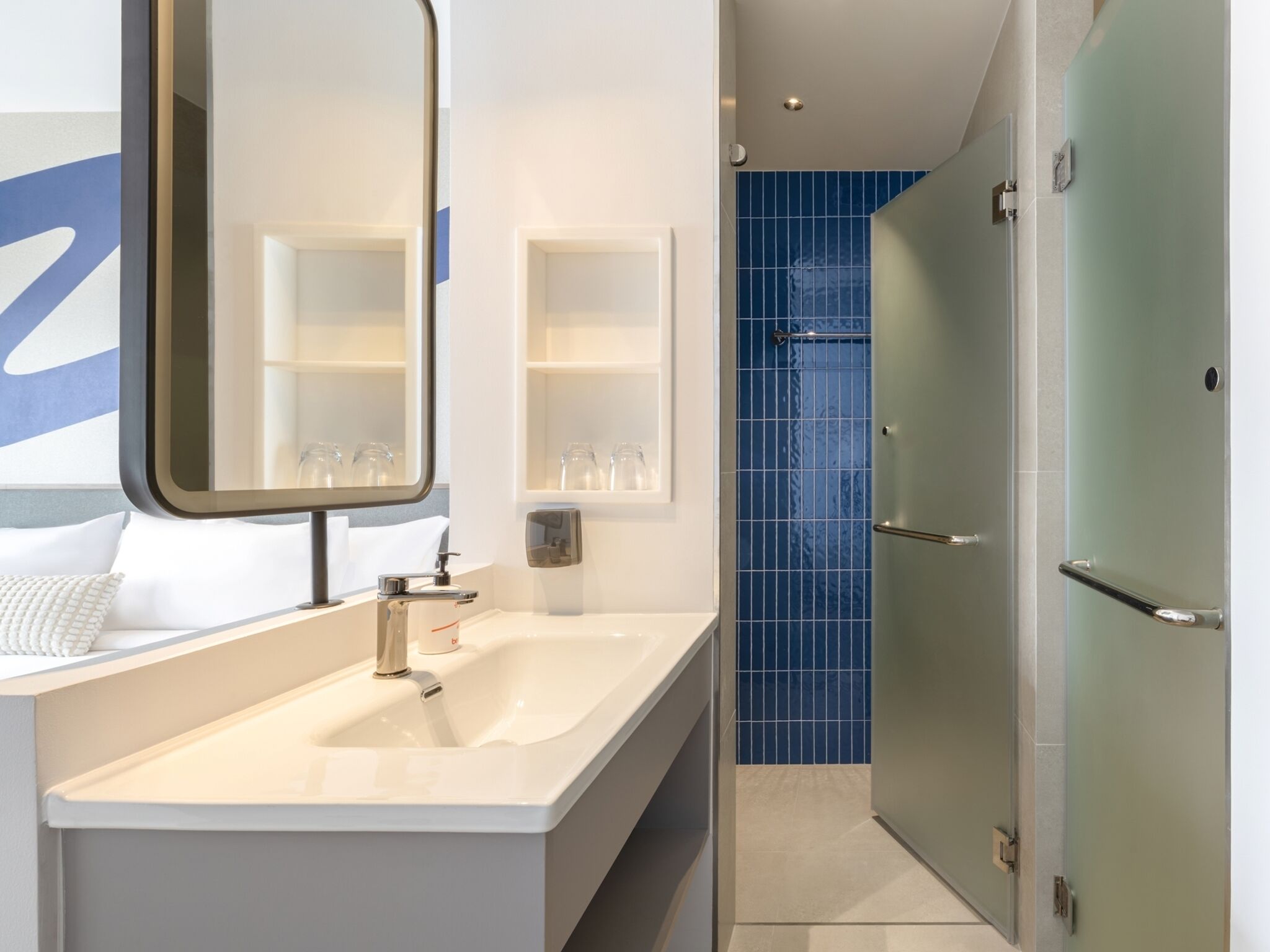 A modern bathroom with a large mirror, a white sink, and a glass shower enclosure.