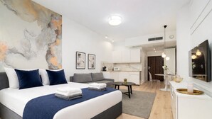 Una habitación de hotel moderna con una cama grande, un sofá, un comedor y una cocina.