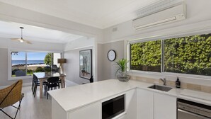 Uma cozinha moderna com uma janela ampla, uma área de refeições com vista para o oceano e um ventilador de teto.