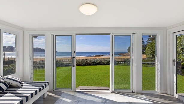 Quarto com uma grande porta de correr de vidro que dá para um gramado e vista para a praia.