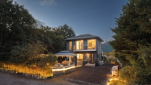 Une maison à deux étages dotée d’un patio, d’un espace salon abrité et d’une entrée bien éclairée.