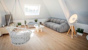 Una stanza in stile loft con una poltrona sospesa, un divano, un tavolino, una lampada da terra e una finestra vista.