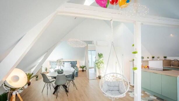 Un loft moderno con angolo ristoro, una poltrona sospesa e una cucina.