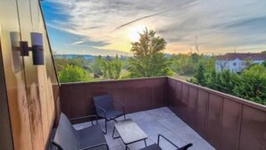 Un balcone con vista sulla città, un tavolo e due sedie.