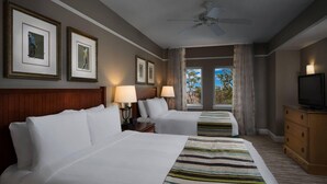 Habitación de hotel con dos camas, un televisor y cuadros en la pared.