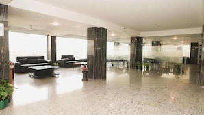 A spacious lobby with a polished floor, seating area, and tall pillars. - Interglobe Oasis (Gurugram)